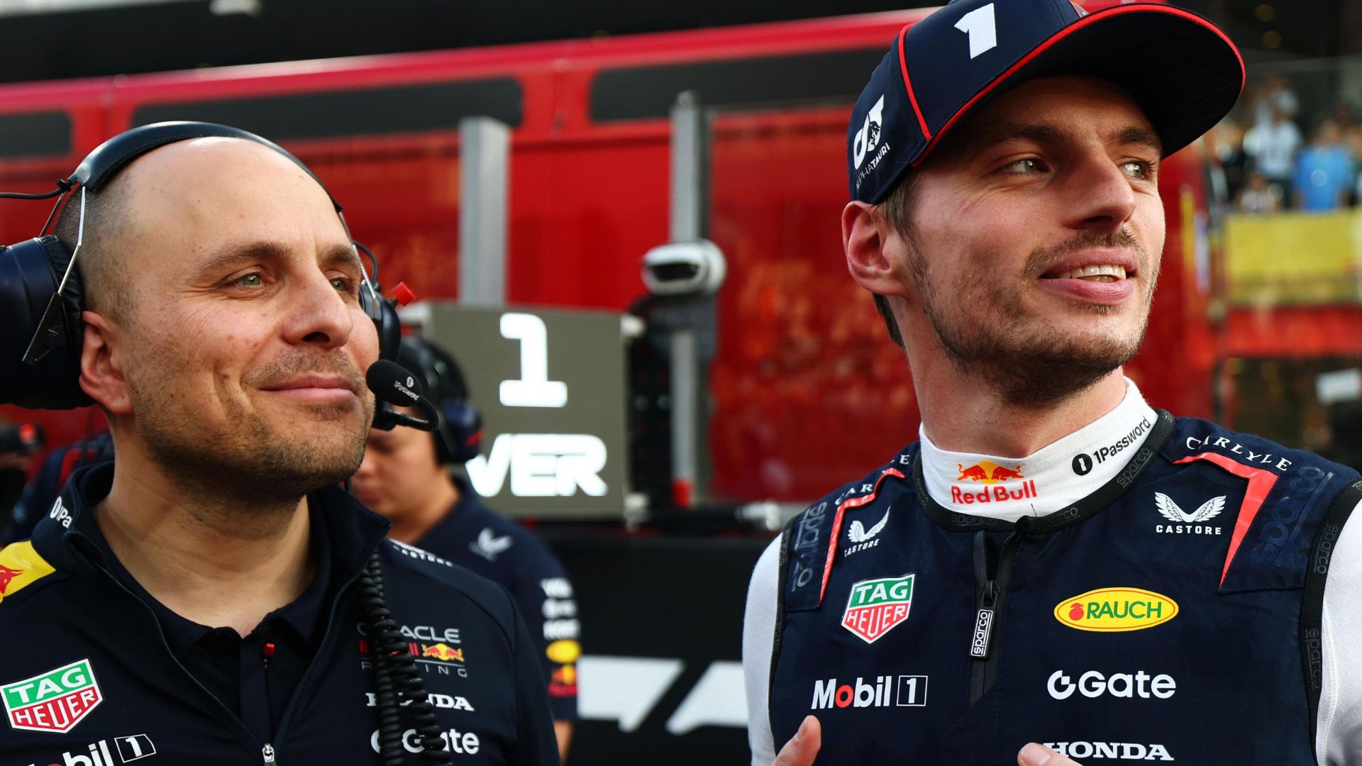 Red Bull Racing Formula 1 driver Max Verstappen smiling alongside his long-time race engineer Gianpiero Lambiase in the pit lane.