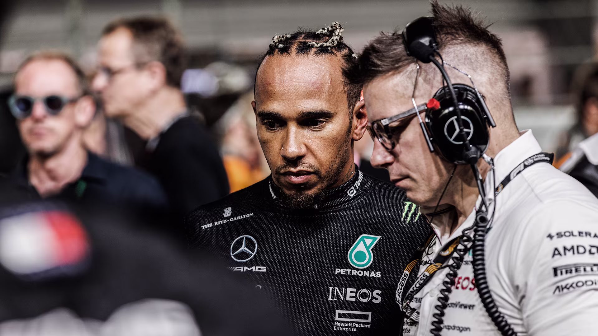F1 driver Lewis Hamilton in his Mercedes race suit looking at data alongside his long-time race engineer Peter Bonnington in the paddock.
